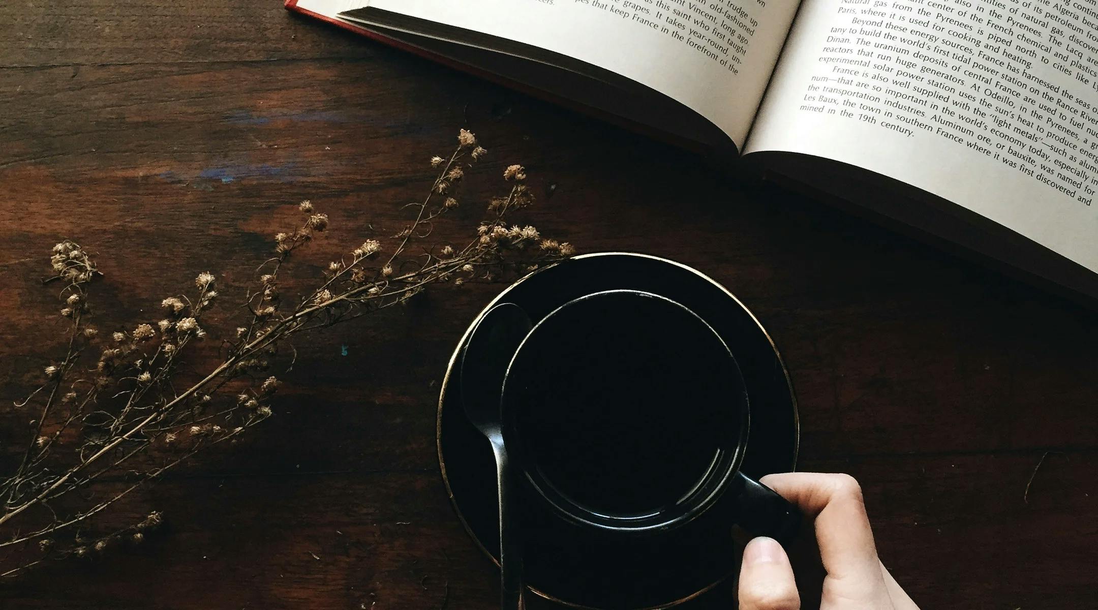 Kaffekopp og oppslått bok på bord